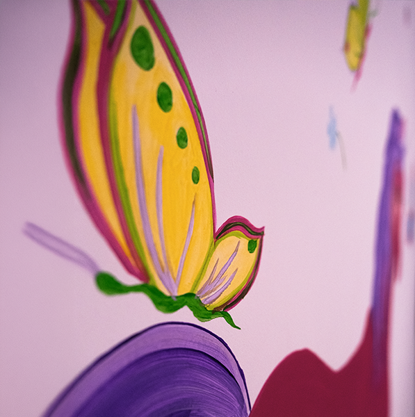 Detalle de mariposa pintada a mano en un mural infantil